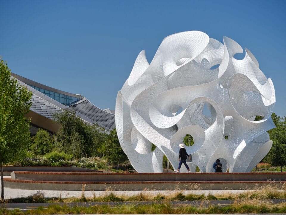 a contemporary white architectural pavilion with undulating forms in the overall shape of a sphere